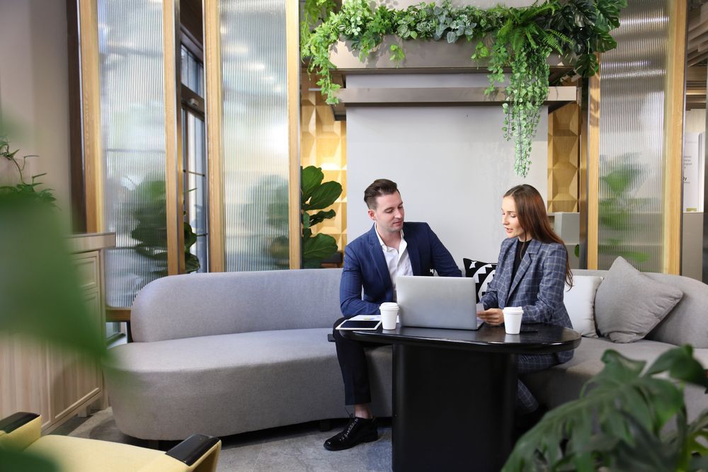 A man and a woman are sitting on a couch looking at a laptop.