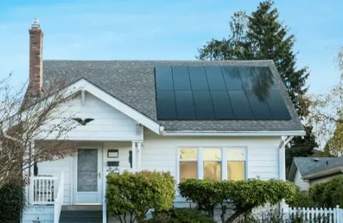 A white house with solar panels on the roof.