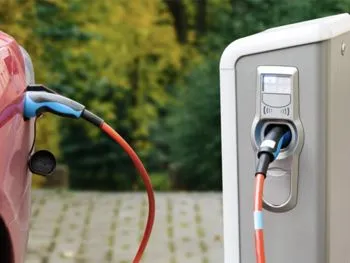 A red electric car is being charged at a charging station.