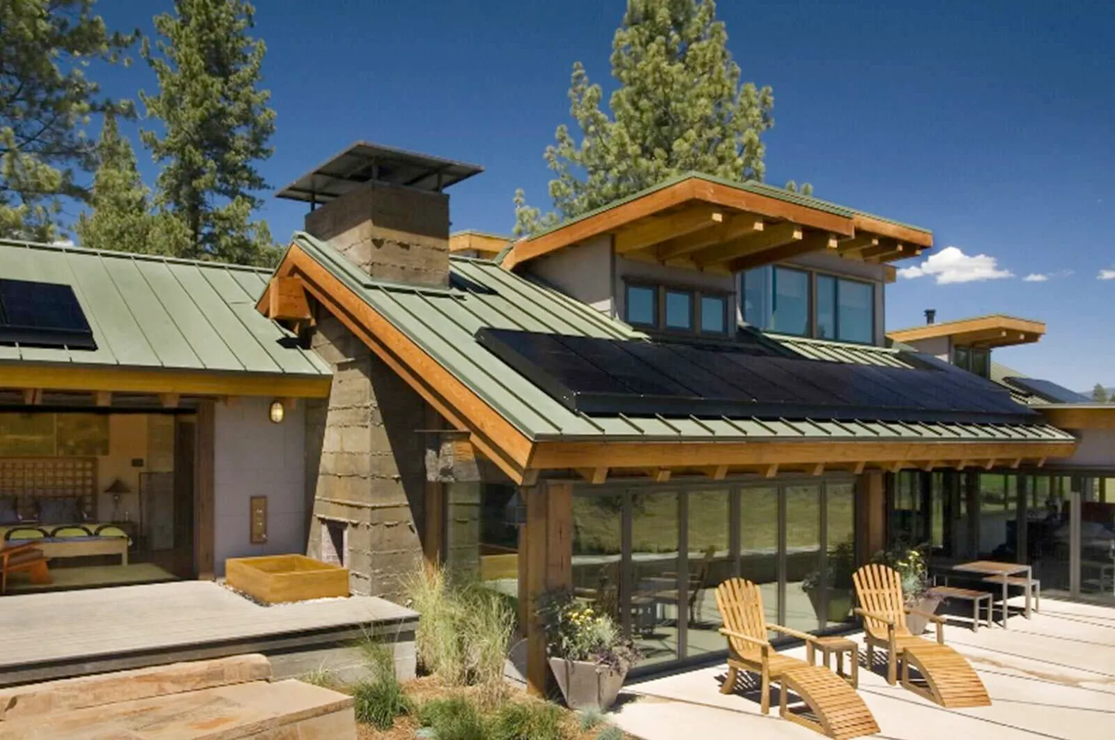 A house with a green roof has solar panels on it