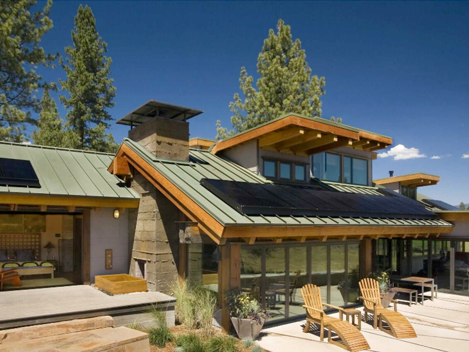 A house with a green roof has solar panels on it