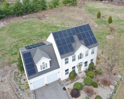An aerial view of a house with solar panels on the roof.