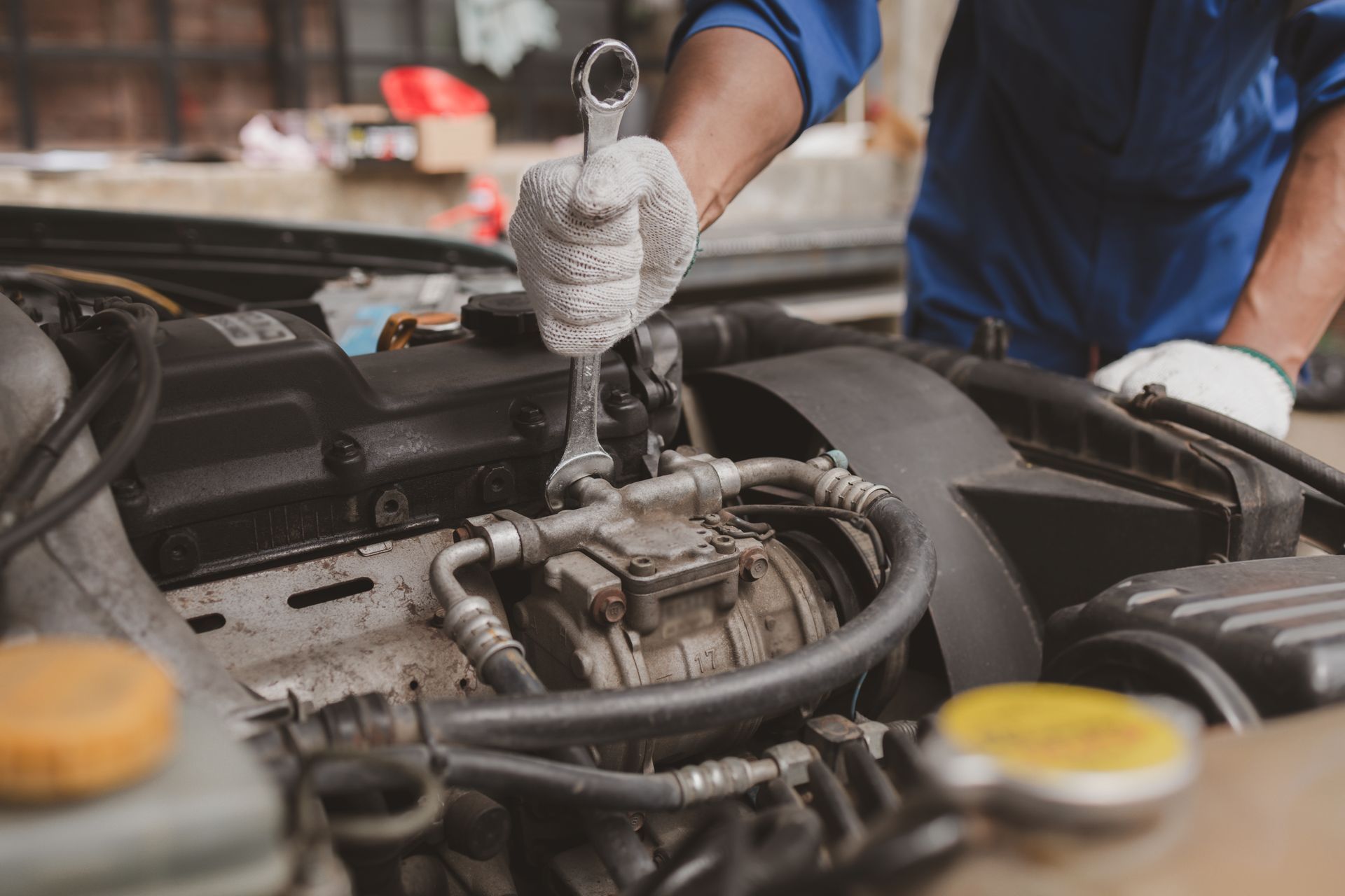 A worker on an auto repair shop applies a coating on a car’s window with a sponge.