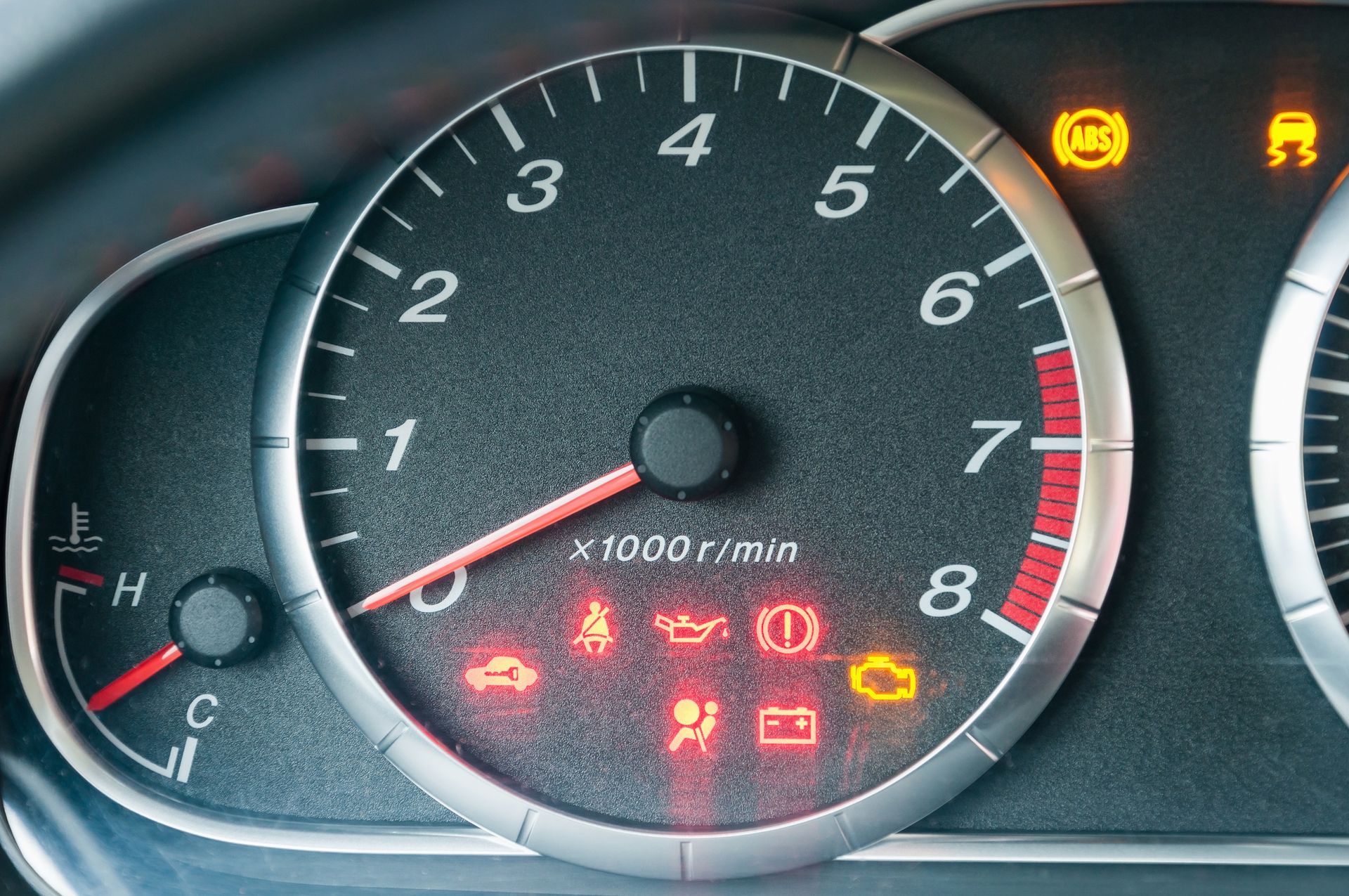 Closeup of a car tachometer with many illuminated indicators.