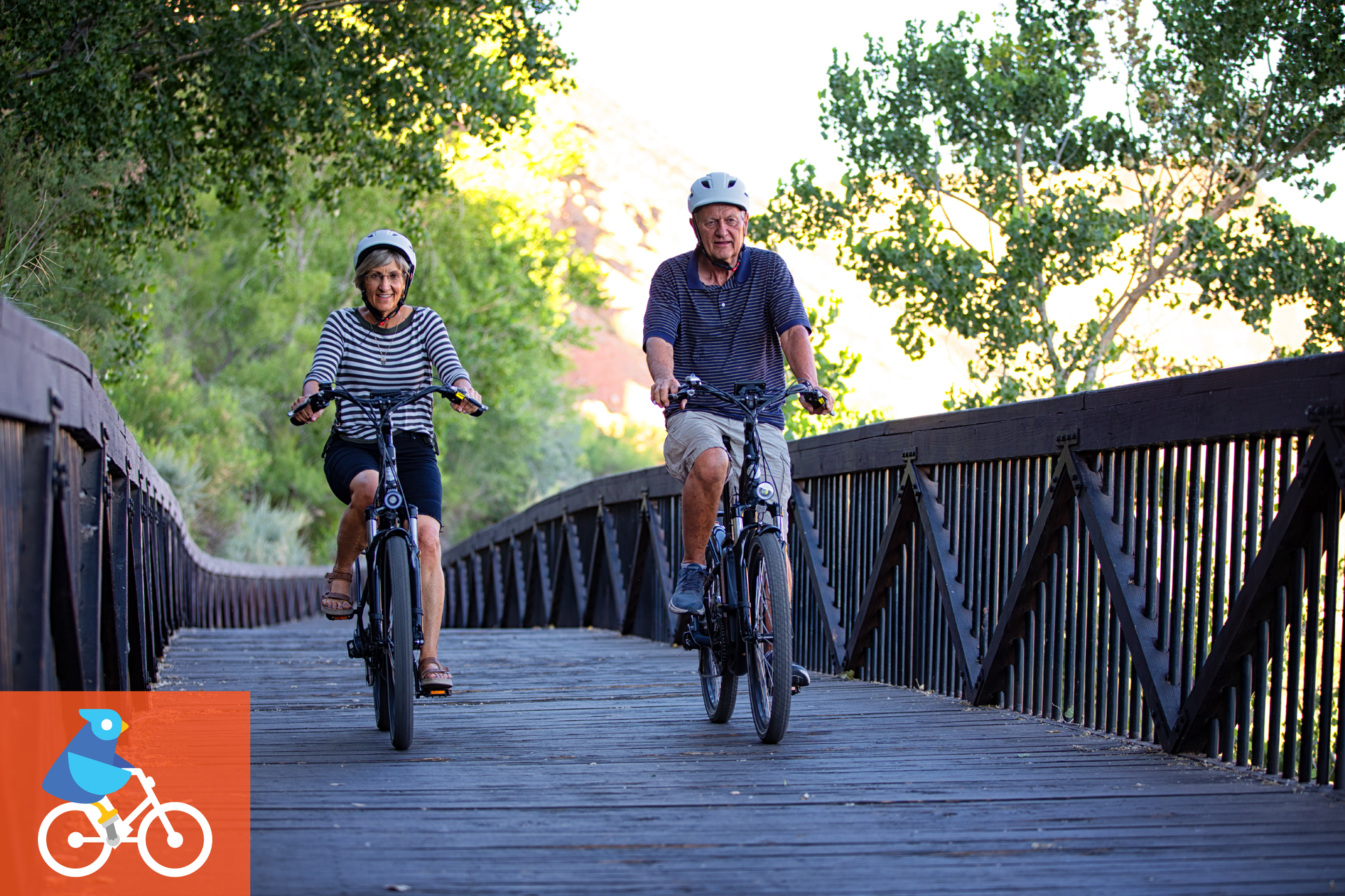 A man and a woman are riding bicycles on a wooden bridge. A bird graphic indicating a bike ride.