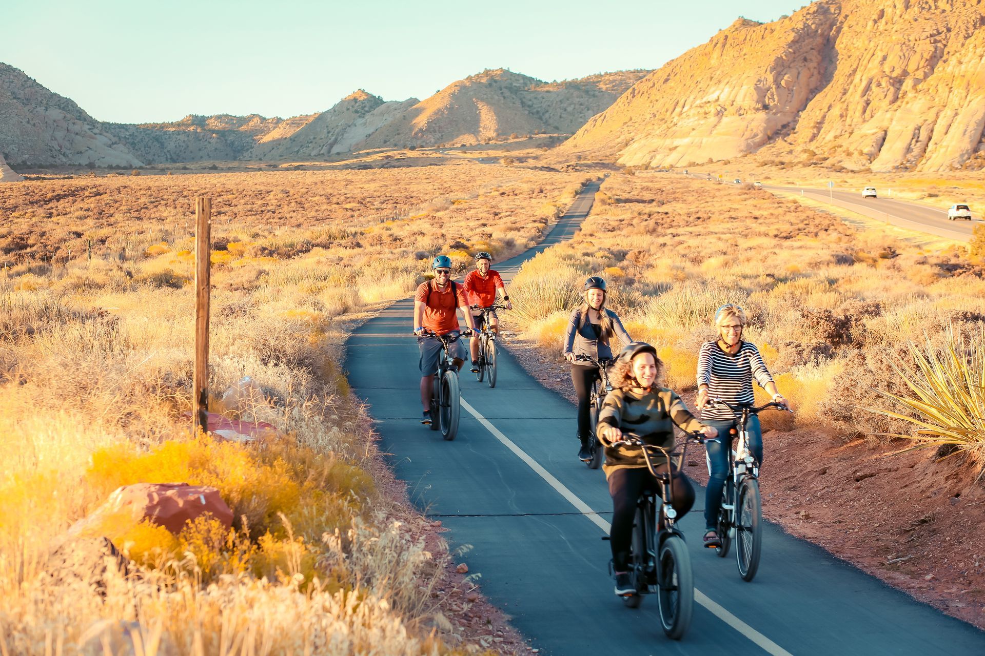 Two people are riding bikes down a paved bike path on the Snow Canyon Loop.