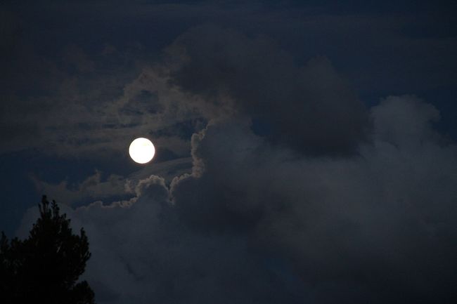 The moon is shining through the clouds in the night sky