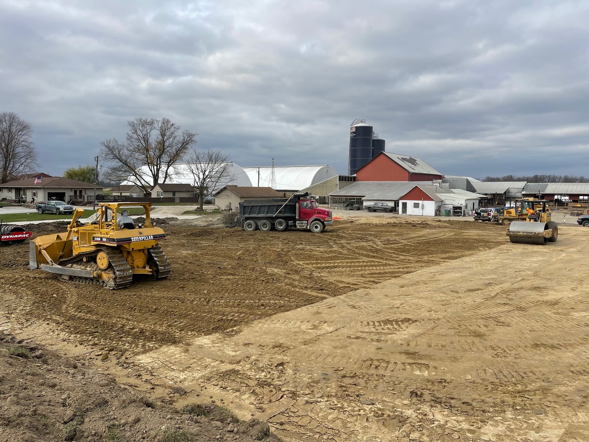 Yellow excavator with a grab attachment clearing a wooded area.