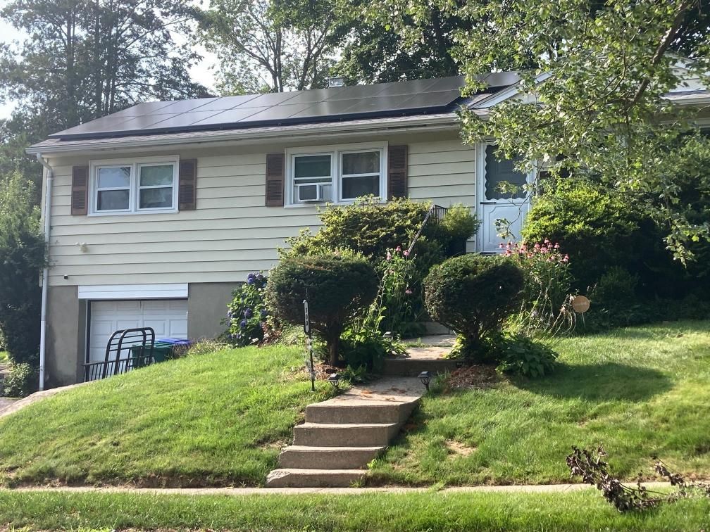 A white house with a solar panel on the roof.