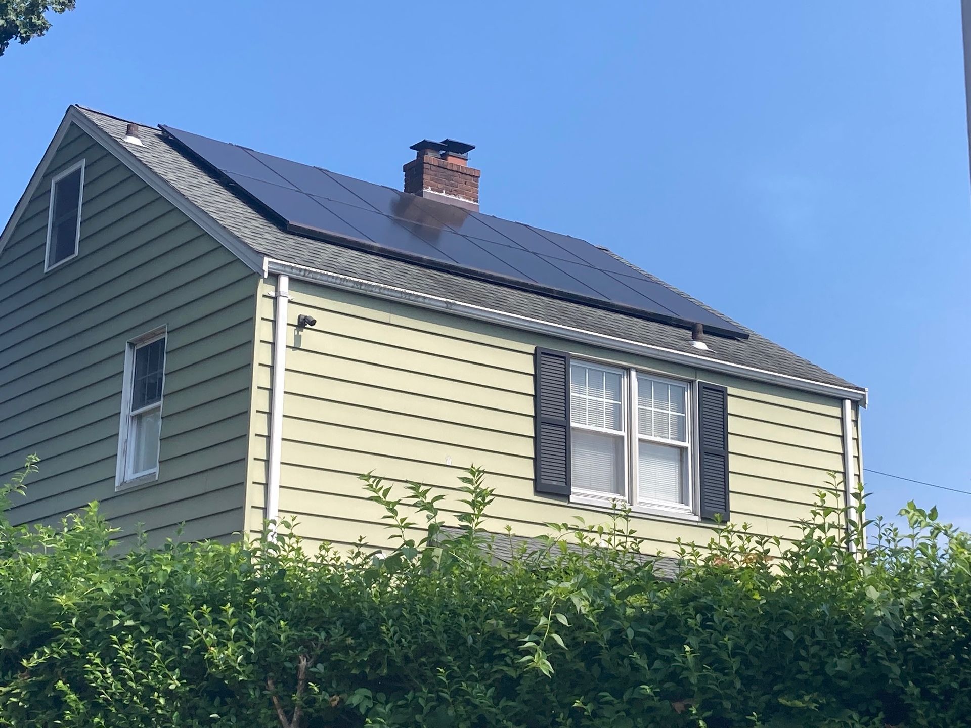 A house with solar panels on the roof and a chimney.