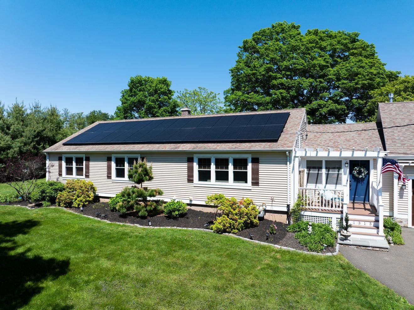 An aerial view of a house with solar panels on the roof.