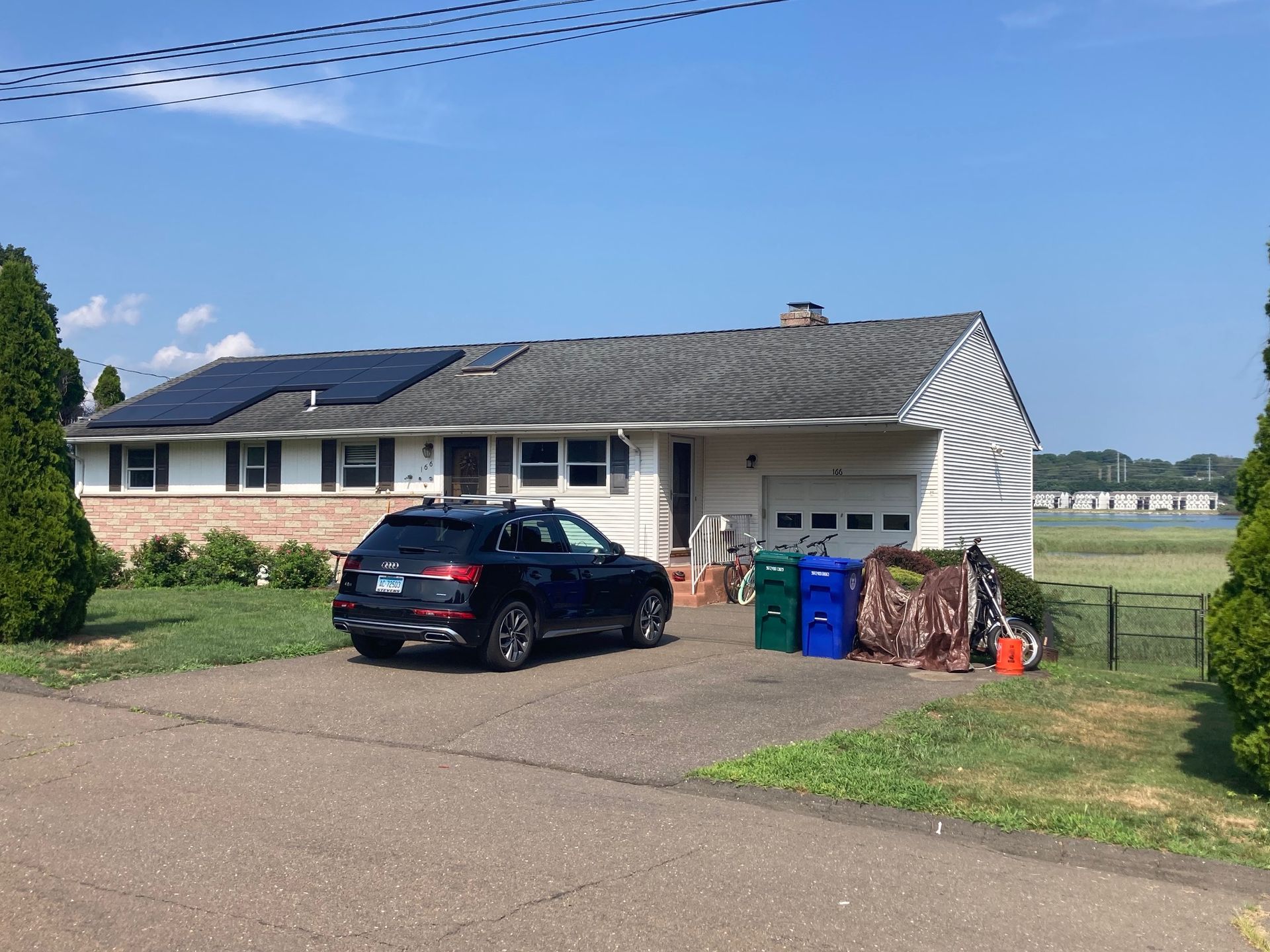 A car is parked in front of a house with solar panels on the roof