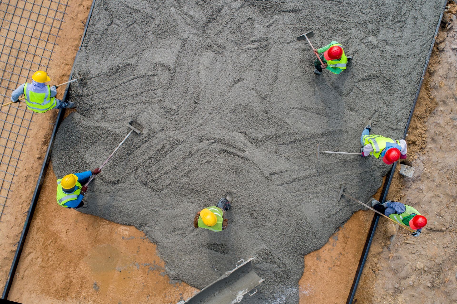 A construction worker pouring a wet concrete at road construction site