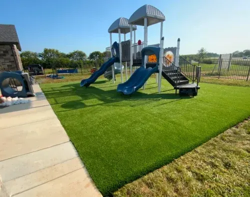 Playground with blue slides and artificial green turf.