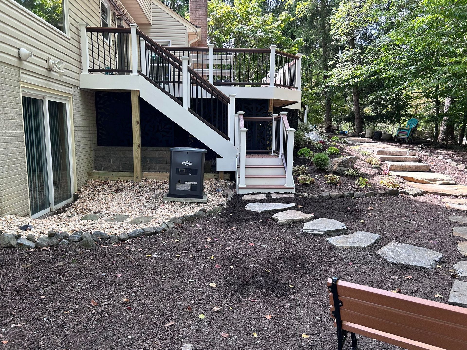 A large deck with stairs leading up to it is in the backyard of a house.