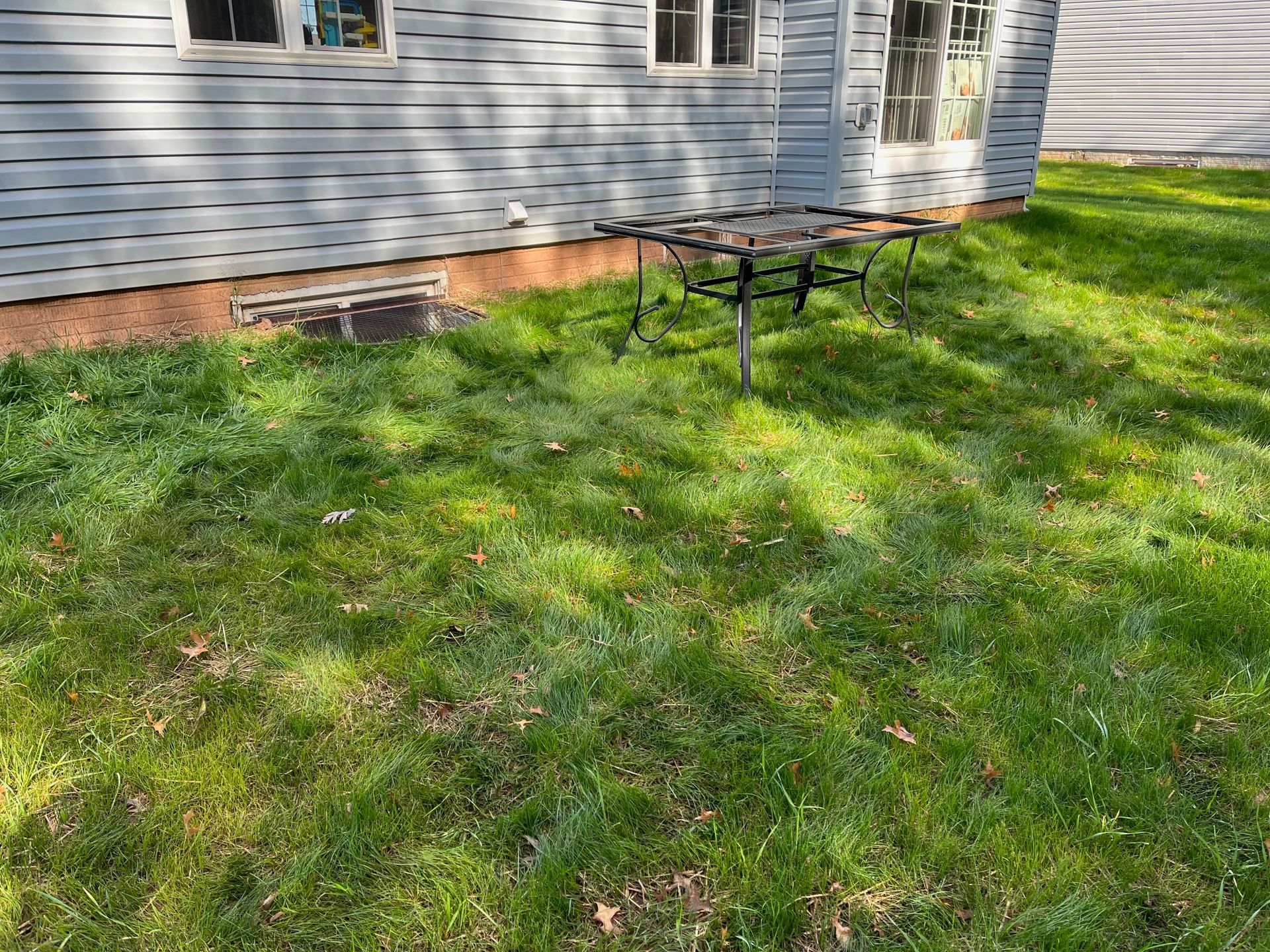 A picnic table is sitting in the grass in front of a house.