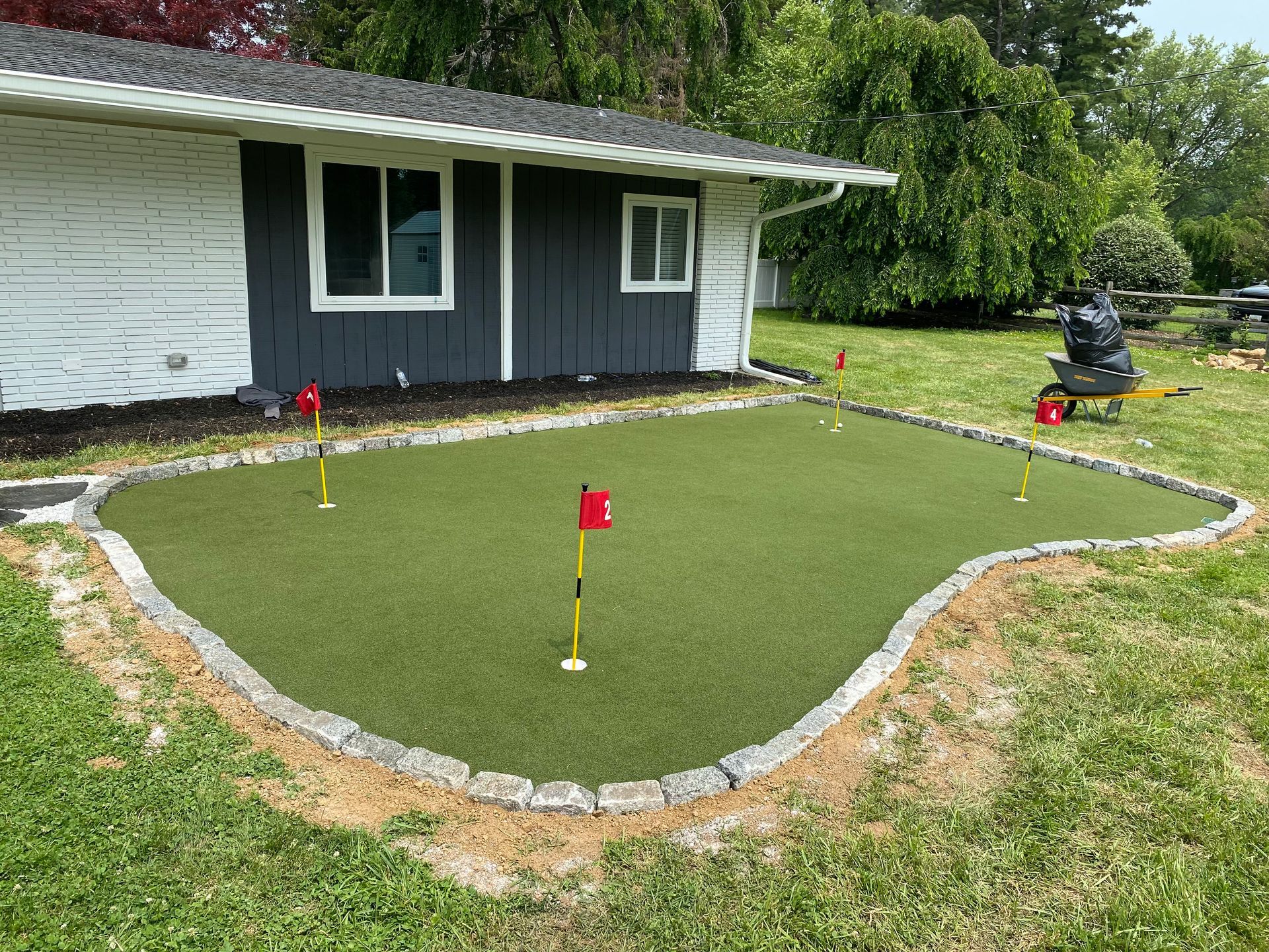 A house with a putting green in front of it.