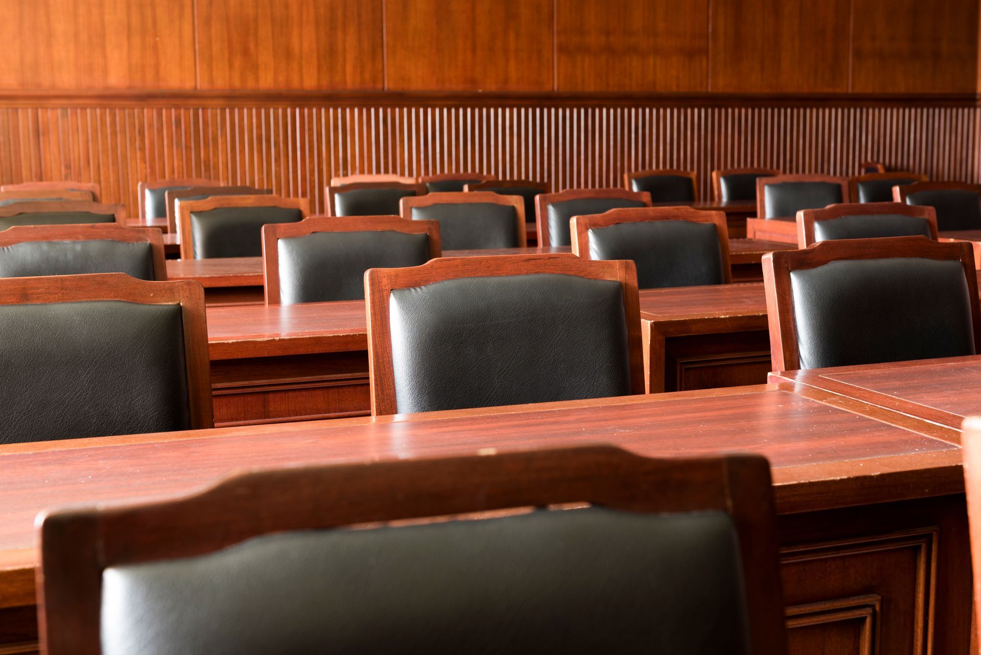 Wooden courtroom with empty desks and chairs.