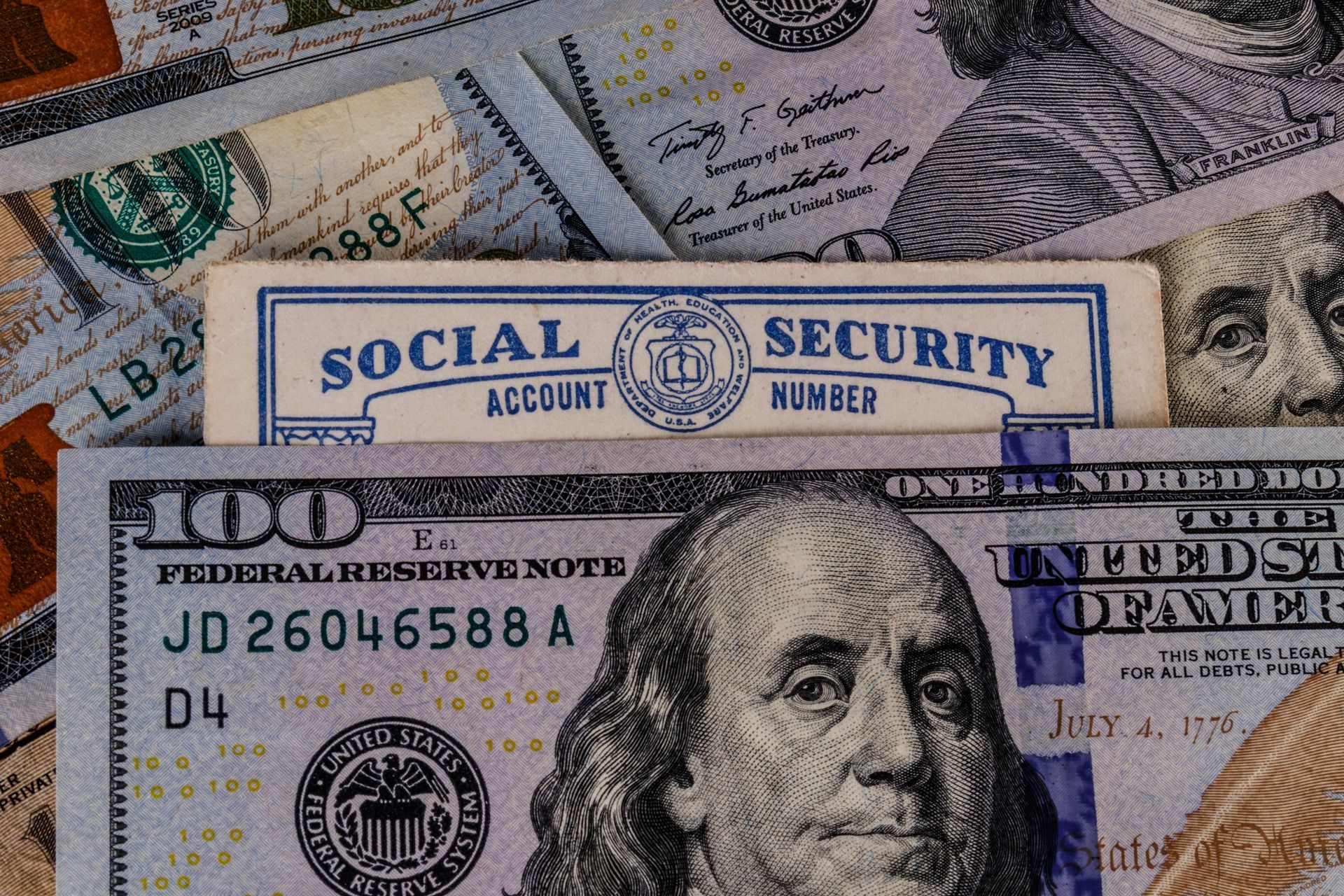 U.S. dollar bills with a Social Security card partially visible in the background