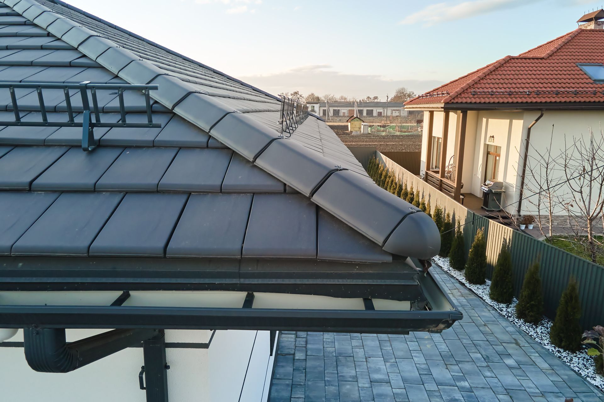 Gray roof tiles with a gutter, a view of a neighborhood.