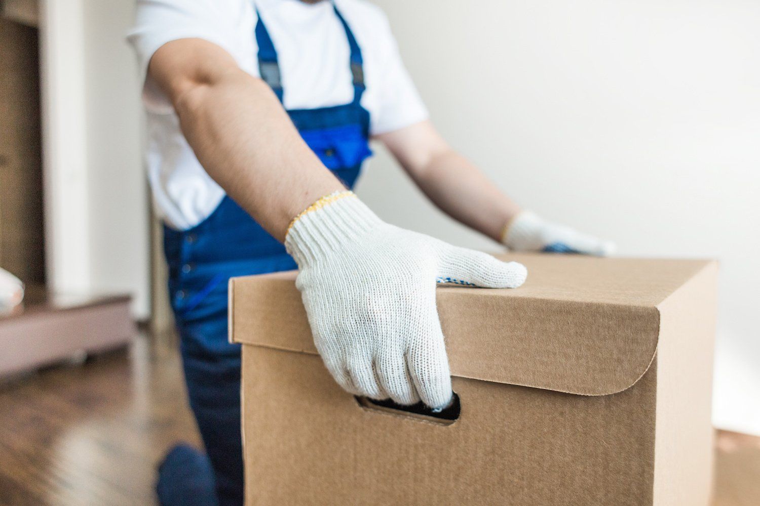 Delivery man stacking cardboard boxes for moving into an apartment.