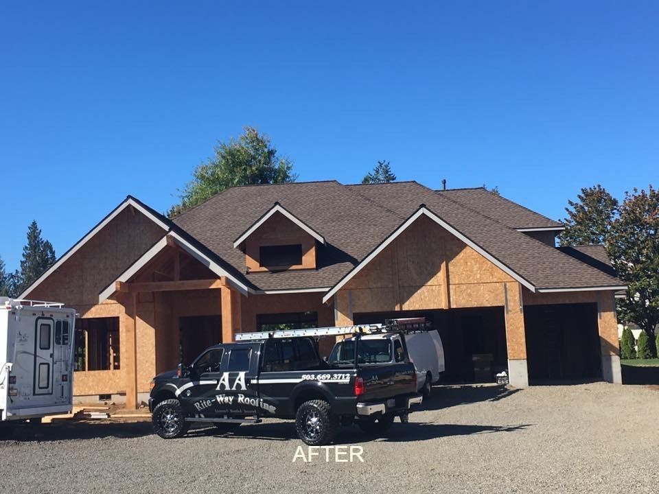 A house under construction with a new roof, parked truck in front, clear blue sky.