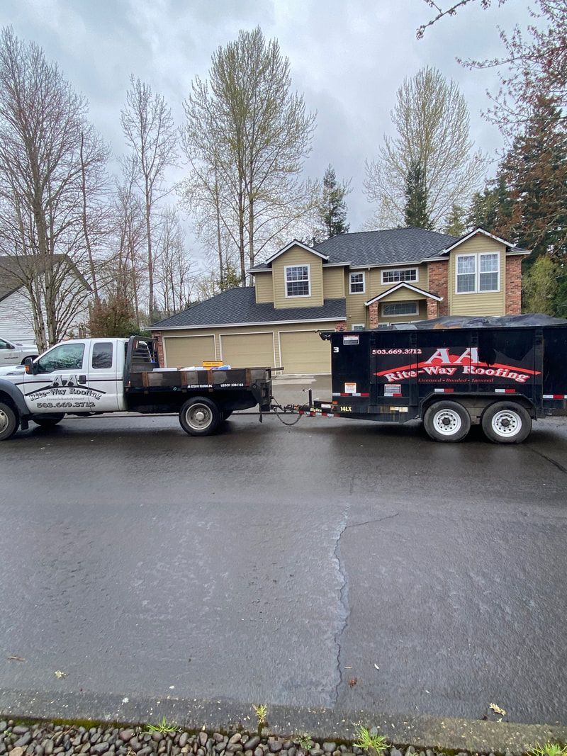 Truck towing a trailer in front of a house with a dark roof on a cloudy day.