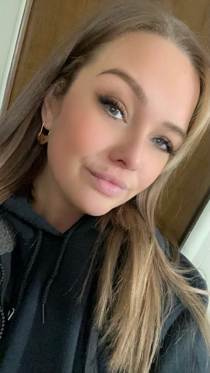 Blonde woman with brown eyes wearing a black hoodie, looking toward the camera with a slight smile.