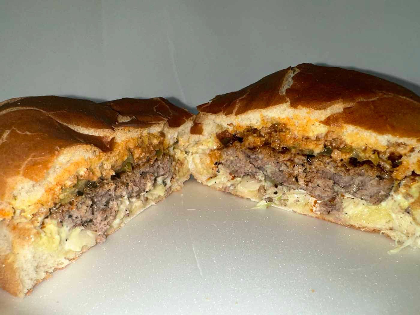 A hamburger is cut in half on a white plate.