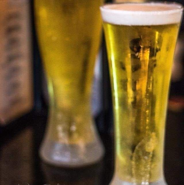 Two glasses of beer are sitting on a table