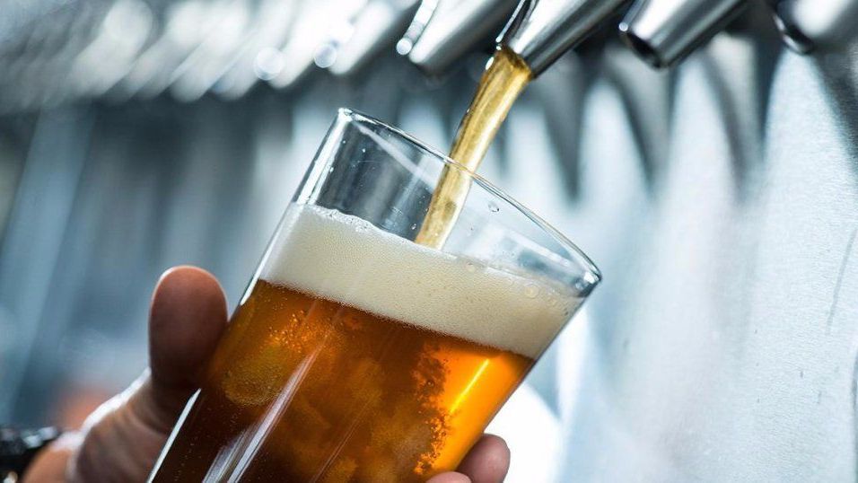 A person is pouring beer into a glass from a tap.
