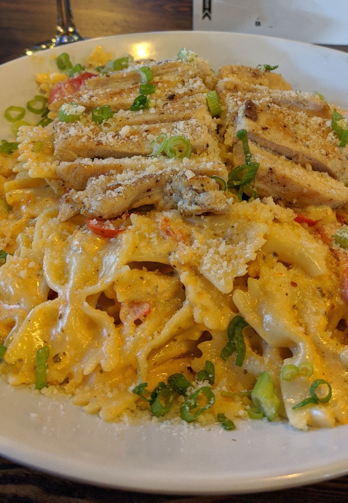 A close up of a plate of pasta with chicken and onions on a table.