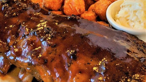 A white plate topped with ribs and fried potatoes