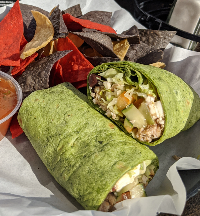 Two green wraps next to a bowl of tortilla chips