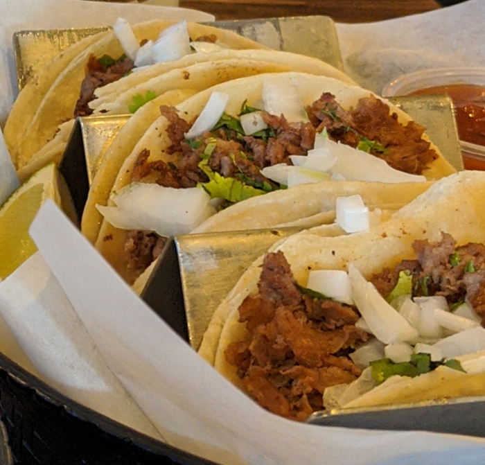 A bunch of tacos with meat and onions in a basket