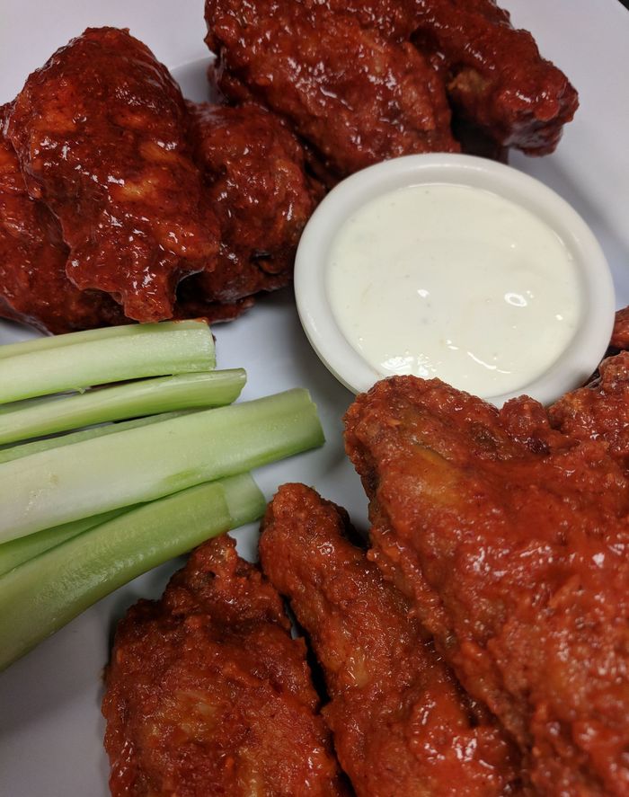 A plate of chicken wings with celery and ranch dressing