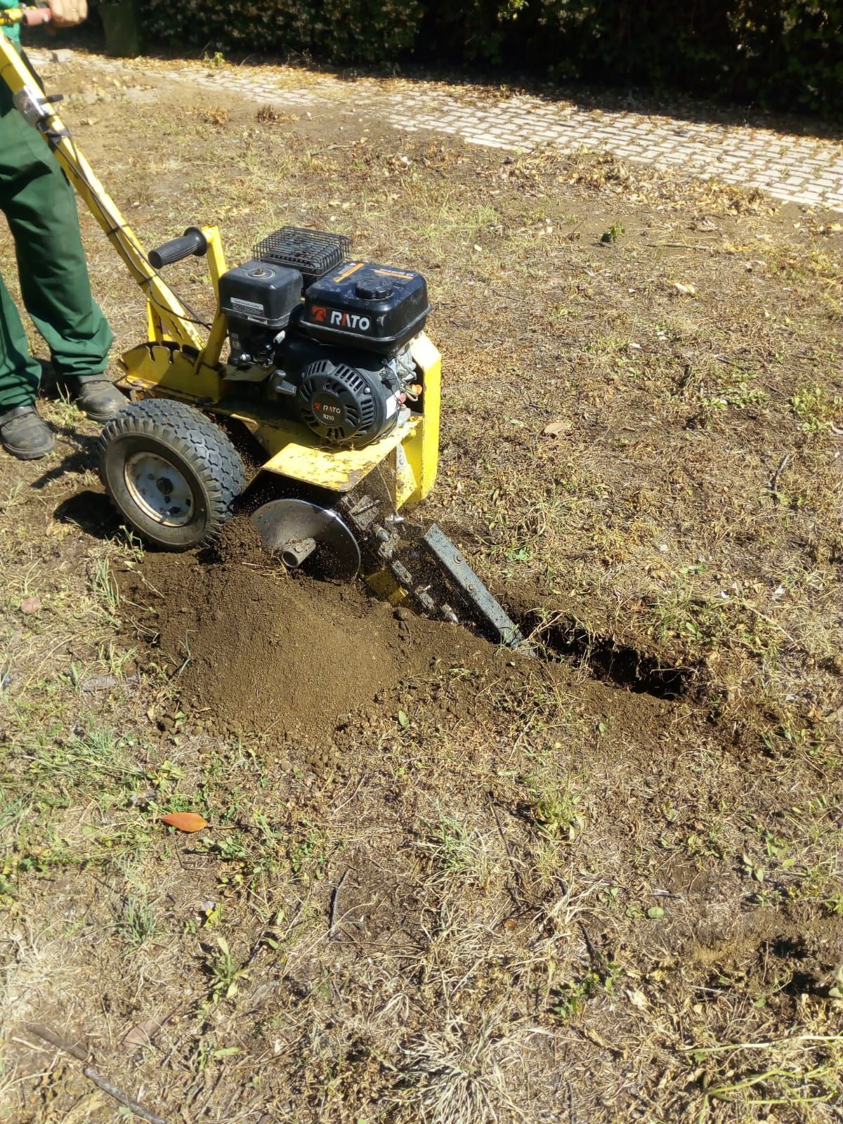 Una persona sta usando un tosaerba giallo per scavare una buca nel terreno.