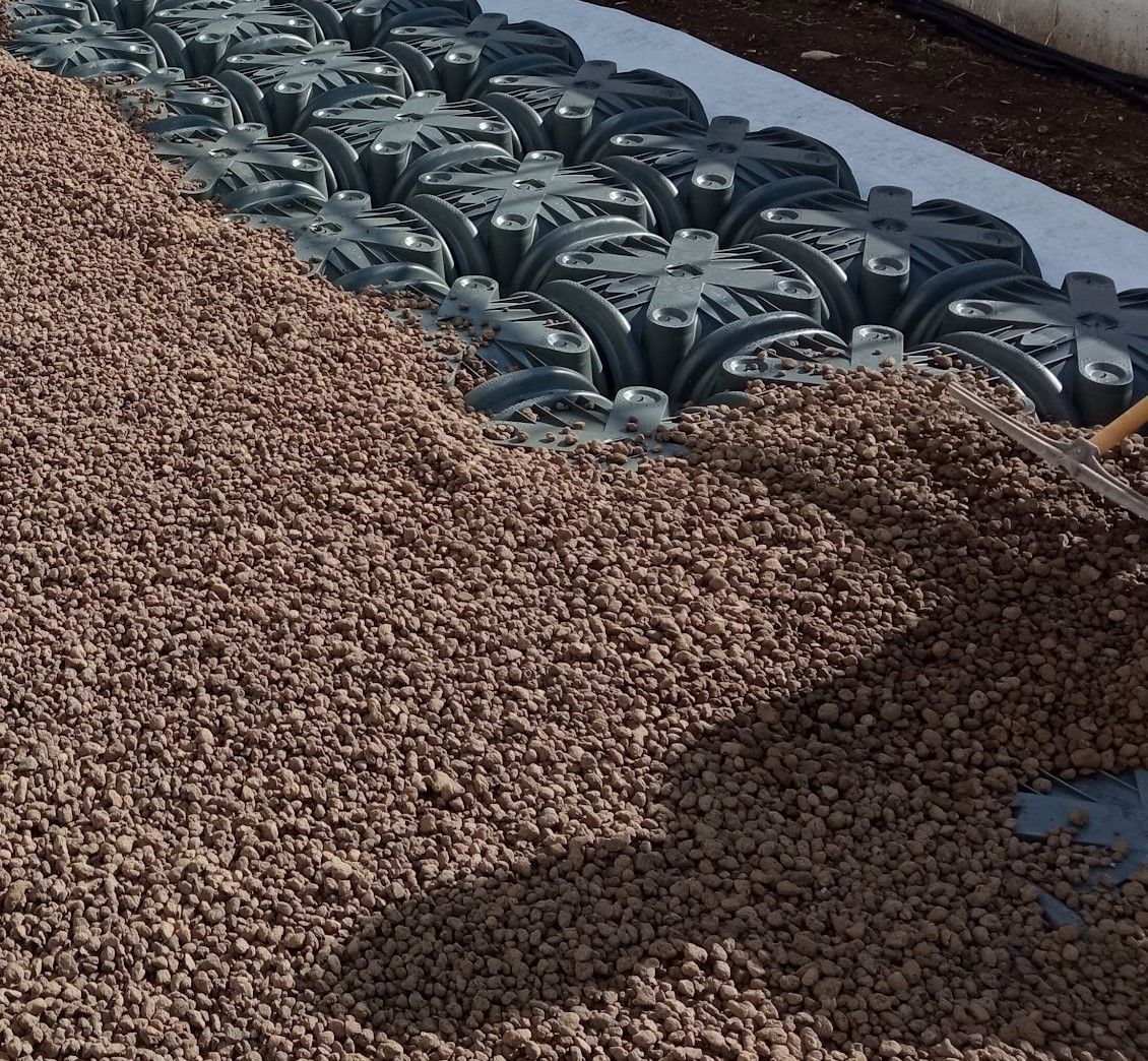 Una persona sta stendendo della ghiaia sopra un mucchio di ghiaia.