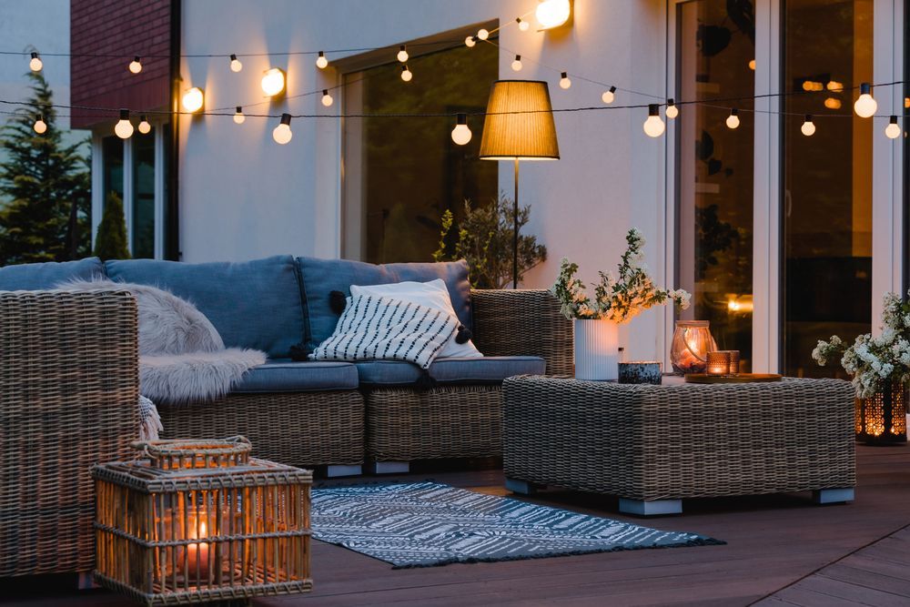 Un patio con divano, sedie, tavolo e lanterne di notte.