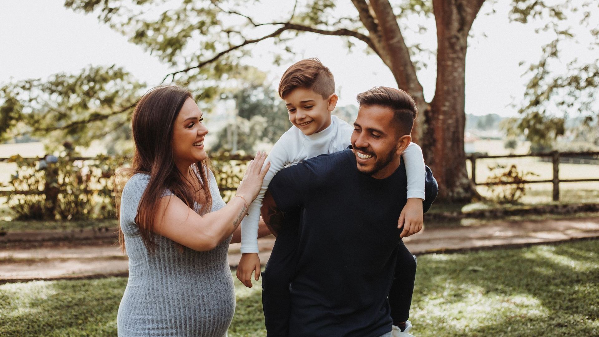 A laughing family is standing in front of a tree