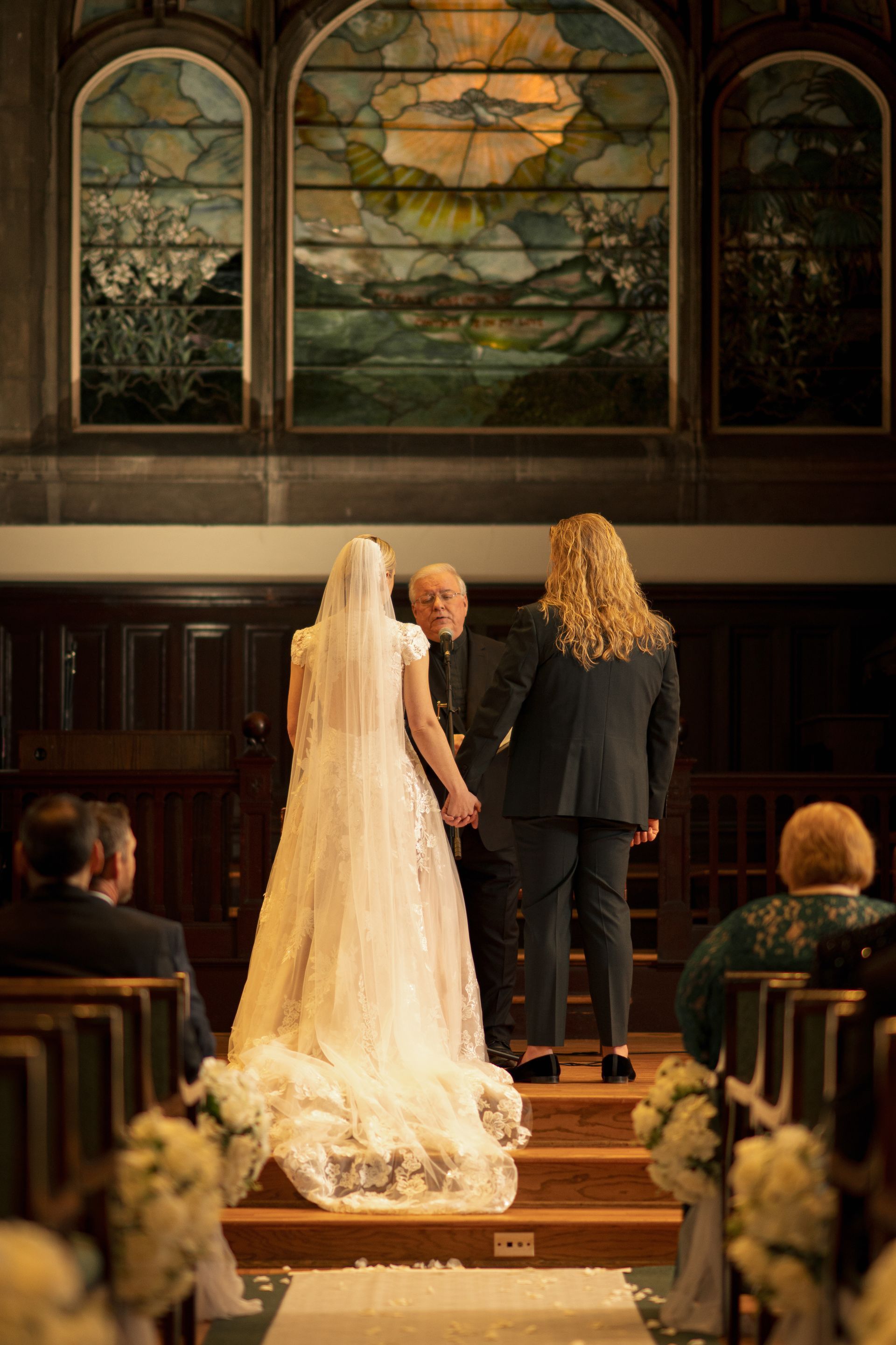 Couple embraces, man kissing woman's forehead, in front of a tall building.