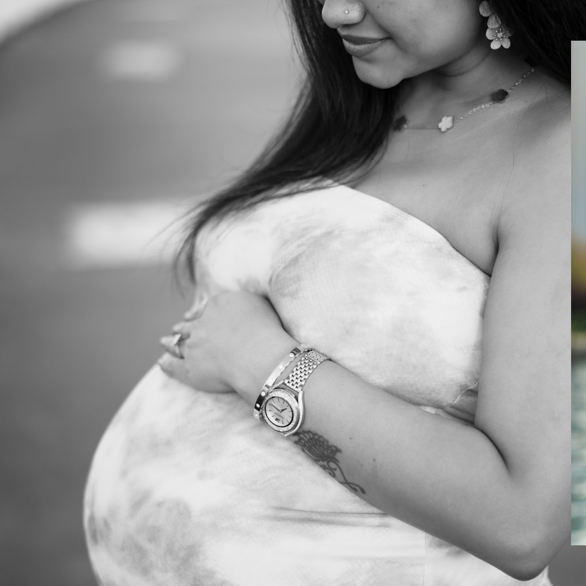 Pregnant person in a strapless dress cradling belly, wearing jewelry. Black and white photo.
