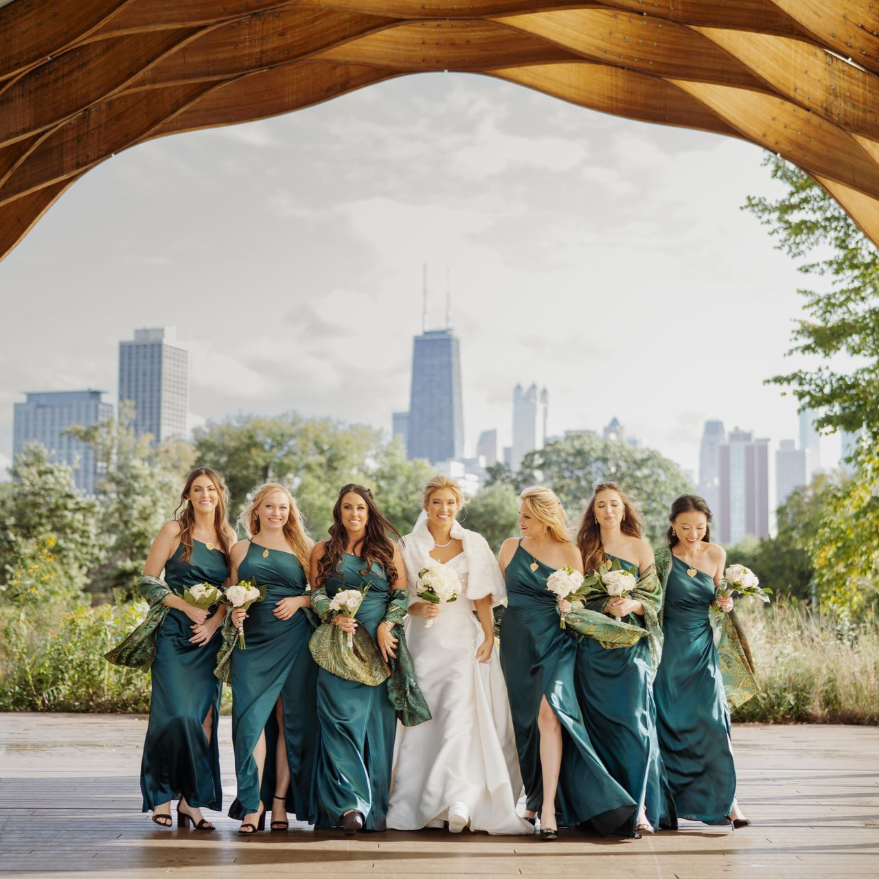 Bride and bridesmaids in teal dresses with bouquets, Chicago skyline backdrop.