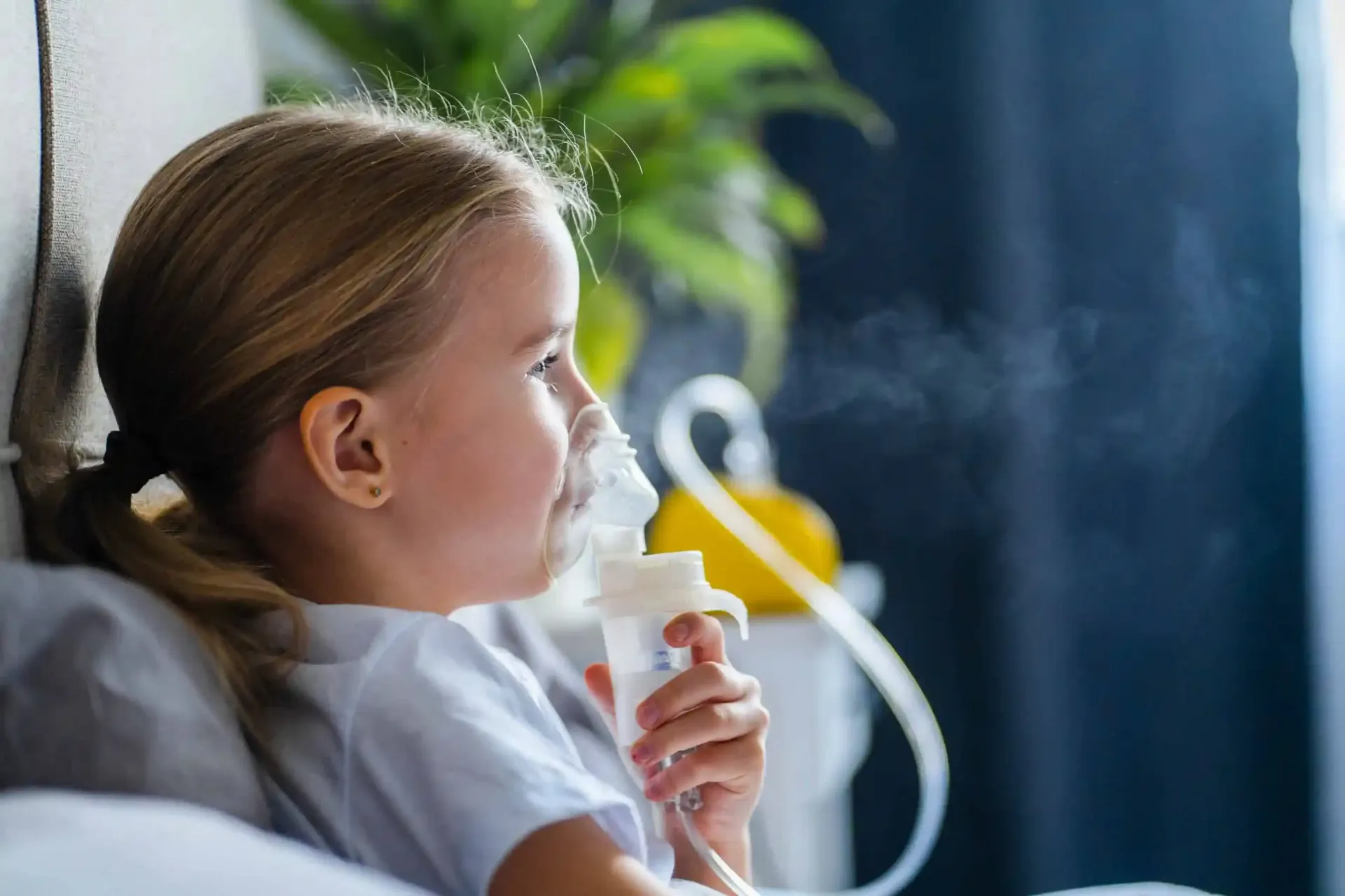 A little girl is using an oxygen mask in bed.