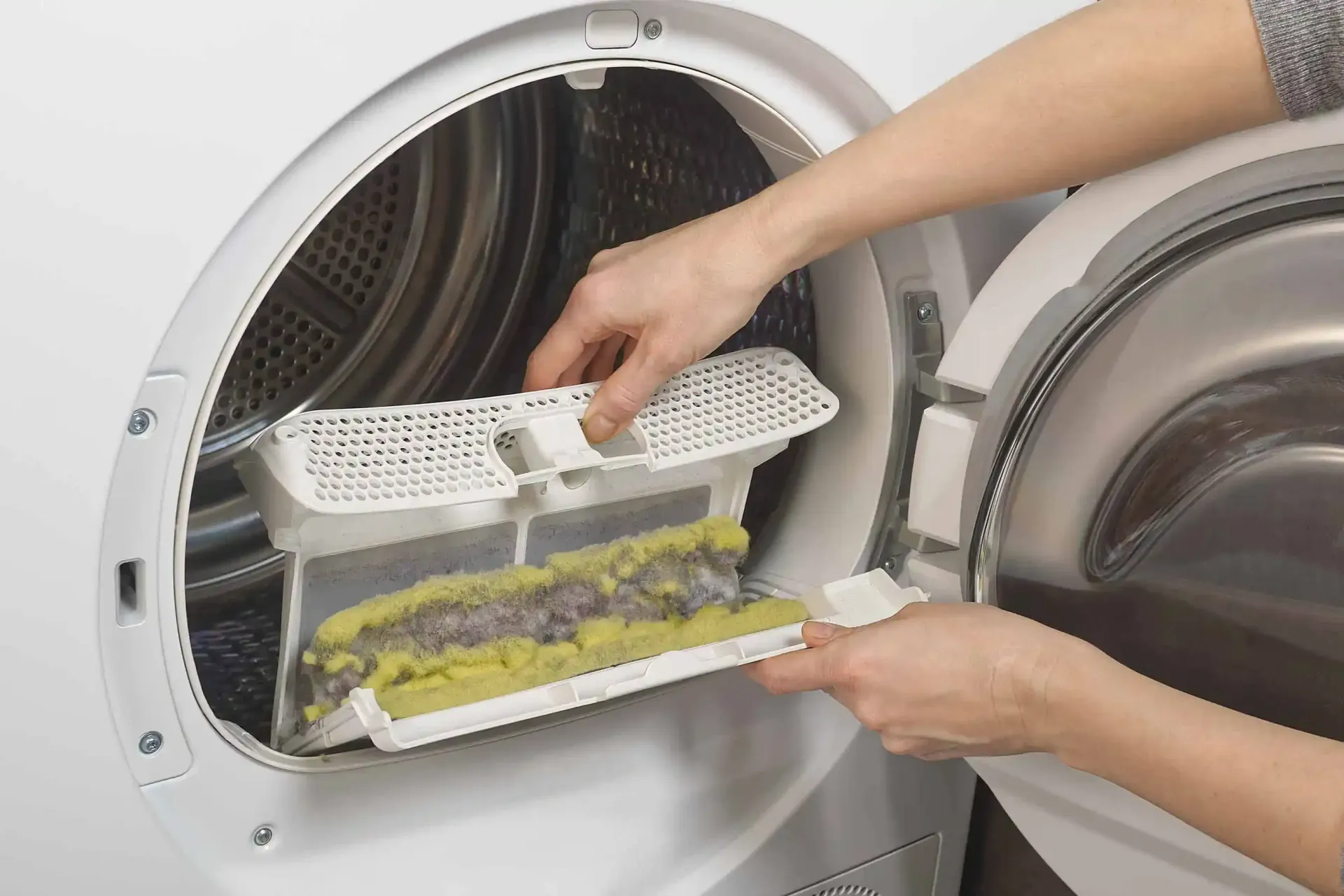 A person is taking a filter out of a washing machine.