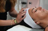 Woman receiving a facial massage with a white headband in a spa setting