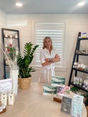 Woman standing in a bright boutique with shelves of candles and packaged goods