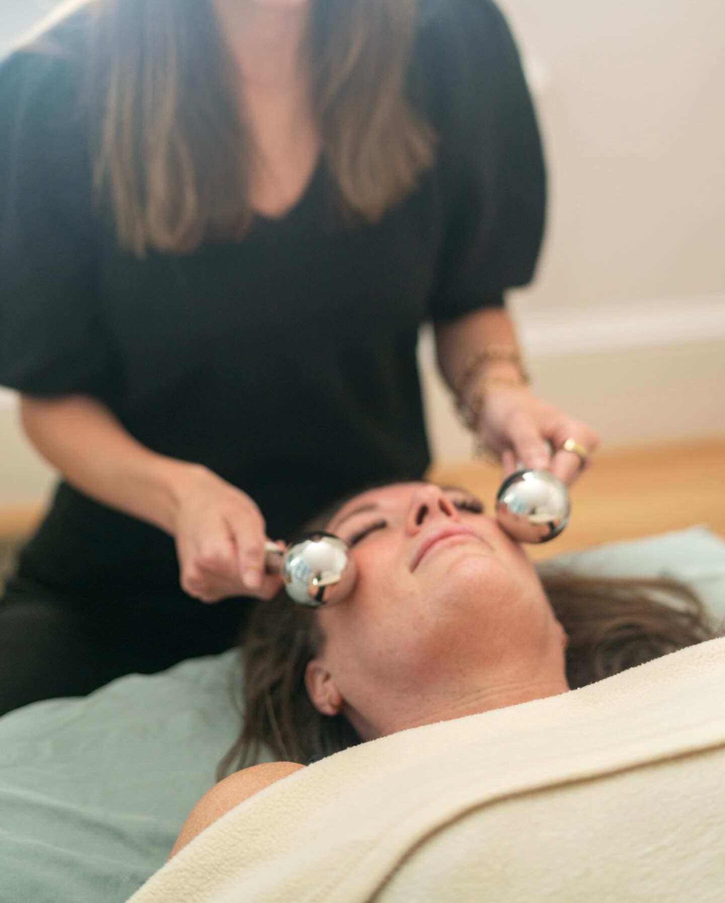 Person receiving a facial massage with metal rollers on a spa bed