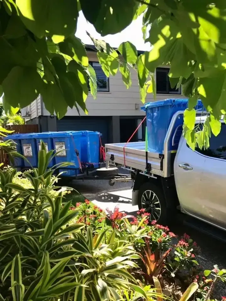 A Truck With a Trailer Carrying Large Blue Bins — Blondies Bins in Airlie Beach, QLD