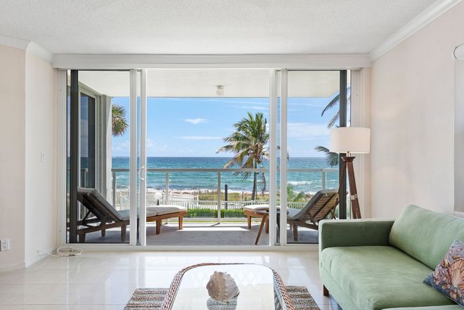 A living room with a green couch and a view of the ocean